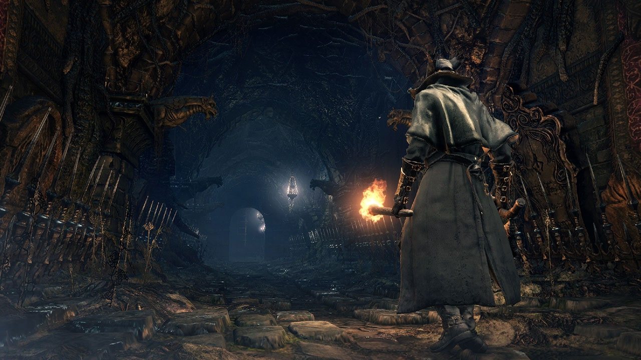 Official screenshot: the hunter seen from behind, holding a torch in a stone corridor.